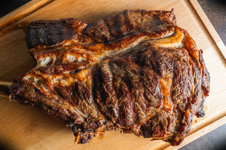 Tomahawk steak poslužen za stolom s prilozima